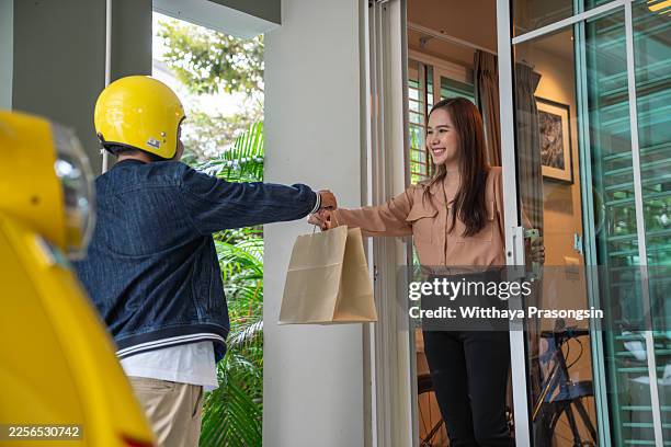 courier delivering takeaway food to smiling woman at home - contactless delivery stock pictures, royalty-free photos & images
