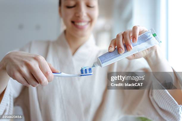 close up of woman using toothpaste while brushing teeth in the morning - toothpaste stock pictures, royalty-free photos & images