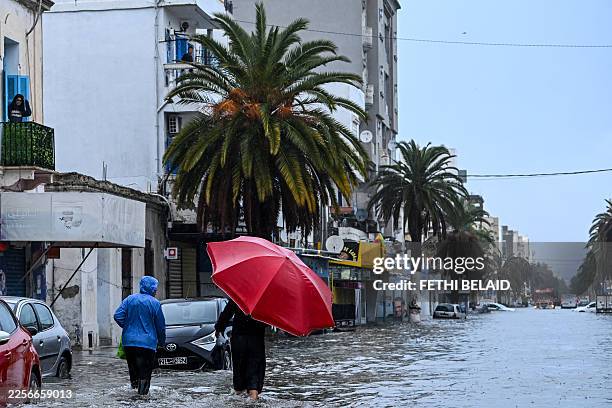 Residents make their way through flood waters, in La Goulette near the capital Tunis, on Januray 20, 2026. Flooding across Tunisia has killed three...