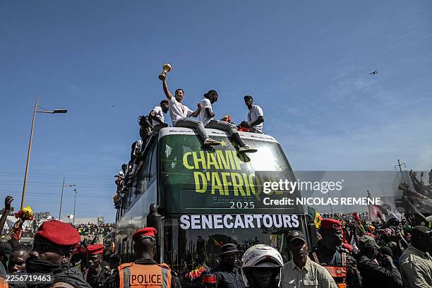 Senegal's Football Team players greet a crowd of supporters while riding on an open busduring a trophy parade in the streets of Dakar on January 20,...