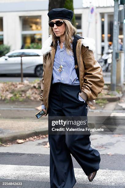 Guest wears brown leather shoes, a black hat, a light blue striped shirt, black trousers and a beige leather jacket outside Dolce & Gabbana show...