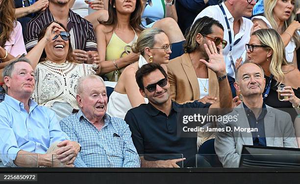 Former men's world number one Roger Federer acknowledges fans as he sits next to Rod Laver at the Women's Singles First Round match between Aryna...
