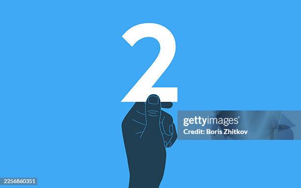 hand holding number 2 sign on blue background - number 2 stock pictures, royalty-free photos & images
