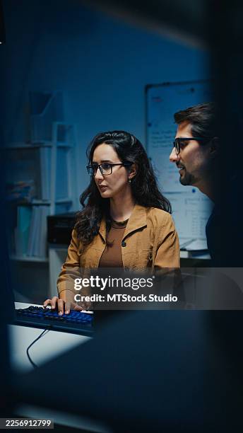 young latin software developers team meeting discussing source code on desktop monitor working late in dark office at night. artificial intelligence and programming concept. - python code stock pictures, royalty-free photos & images