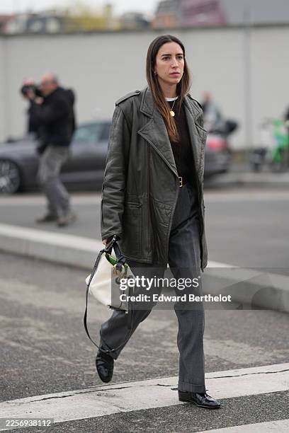 Guest wears long straight dark brown hair with a center part, gold hoop earrings, a white canvas bucket bag with black leather strap and trim, gold...