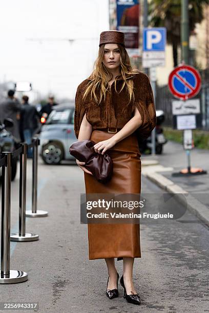 Camille Razat wears a brown velvet short-sleeve top with a front zip and cape-style sleeves, paired with a brown leather midi skirt and brown...