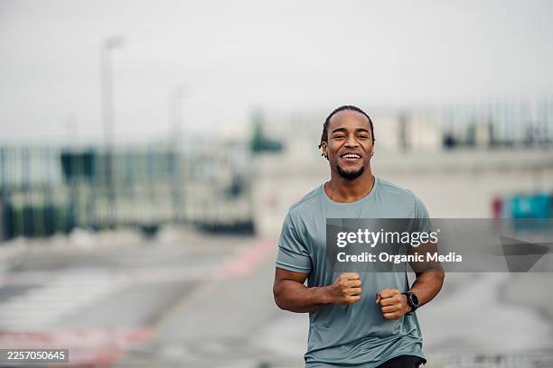young adult black man jogging smiling outdoors - short sleeved stock pictures, royalty-free photos & images