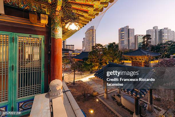 traditional korean temple architecture contrasts with modern cityscape - budismo fotografías e imágenes de stock