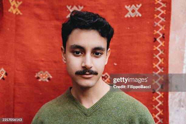 young man posing in front of traditional moroccan rug - north africa stock pictures, royalty-free photos & images