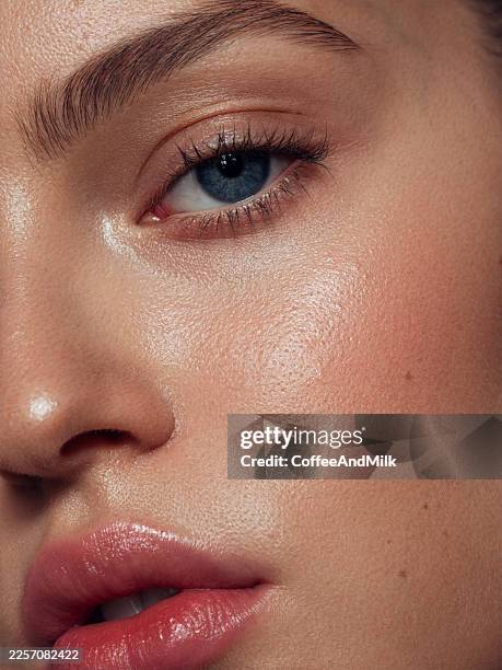 close-up of a woman's face with clear skin, blue eye, and pink lips showing natural glow - skin stock pictures, royalty-free photos & images