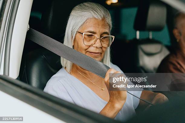 woman fastening seat belt inside car - seat belt stock pictures, royalty-free photos & images