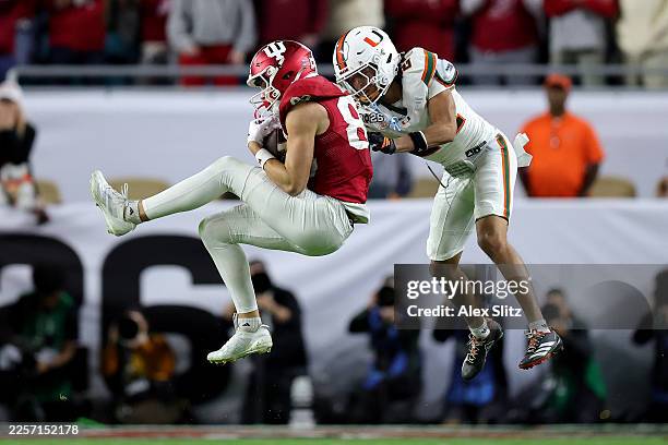 Charlie Becker of the Indiana Hoosiers catches a pass for a first down in front of Ethan O'Connor of the Miami Hurricanes during the fourth quarter...