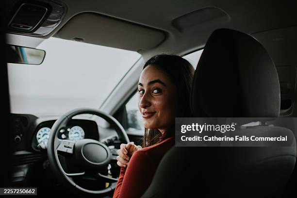 learner driver smiling while seated behind the wheel of a car during a driving lesson. - right hand drive stock pictures, royalty-free photos & images