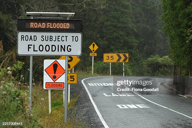 Flooding signs warn drivers at Falls Rd, Warkworth where efforts continue to locate a man reported missing after being swept away in his car while...