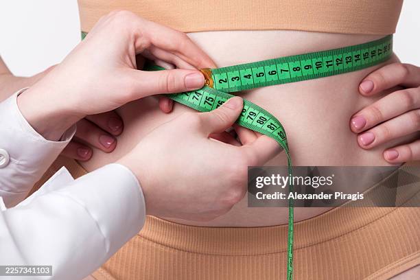the female surgeon is taking a patient's waist measurement using a measuring tape. a plastic surgeon is conducting a preliminary assessment of a patient's physique. the patient is wearing underwear - waist stock pictures, royalty-free photos & images