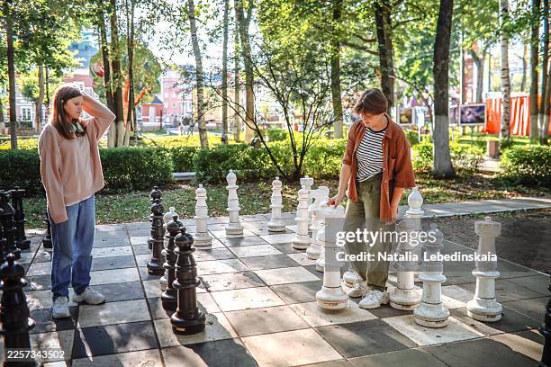 teenagers are competing on a giant chessboard that is part of the park's design. - scacchiera foto e immagini stock