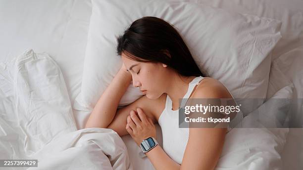 asiatische frau, die einen friedlichen schlaf im bett genießt - schlafapnoe stock-fotos und bilder