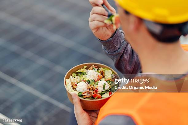 construction worker enjoying healthy salad lunch on solar panel rooftop - eating walnuts stock pictures, royalty-free photos & images