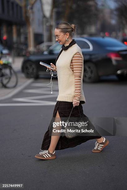 Sonia Sofianidou is seen wearing a cream chunky knitted sleeveless vest with a high neckline from Zara; a beige and white striped long sleeve...