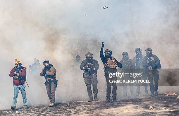 Federal agent lobs a teargas canister towards protesters as agents advance through clouds of tear gas during clashes following the fatal shooting of...