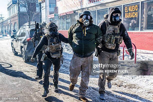 Federal agents detain a protester along a commercial street during clashes following the fatal shooting of a demonstrator earlier in the day, on...