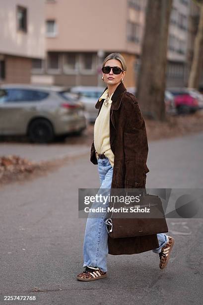 Julia Kammerer is seen wearing a long chocolate brown suede vintage trench coat with a wide lapel collar, button front and a relaxed fit; a butter...
