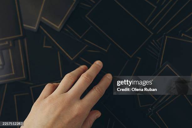 a female hand reaches to scattered dark cards. - face down cards stock pictures, royalty-free photos & images