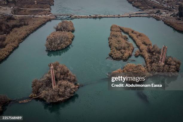 An aerial view shows people cross a damaged bridge over the Euphrates River as Syrian army forces deploy in parts of the eastern province formerly...