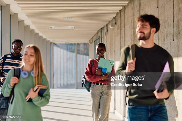 vielfältige studierende, die den universitätsflur entlanggehen - globales dorf stock-fotos und bilder