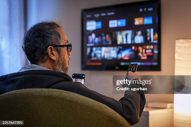 adult man choosing content on smart tv at home - streaming service stock pictures, royalty-free photos & images