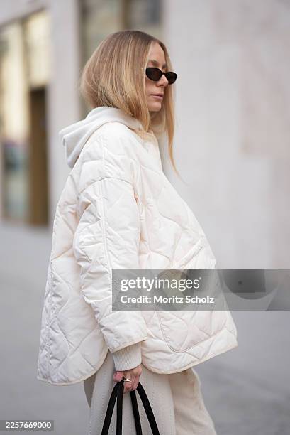 Anouk Delphine is seen wearing a thin cloud dancer white quilted puffer jacket with button front and oversized fit from The Frankie Shop; a cream...