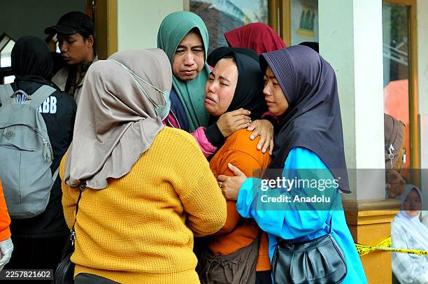 Relatives of victims cry after seeing bodies recovered and taken to a cleaning site at the Disaster Victim Identification after a landslide hit...