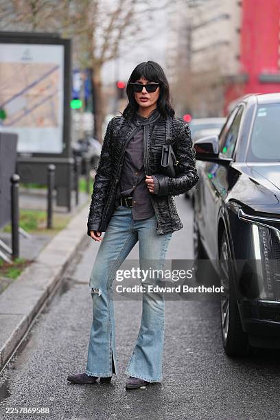 Maria Bernard wears long black hair with full bangs, black rectangular sunglasses, a black leather top-handle bag with a flap front and gold-tone...