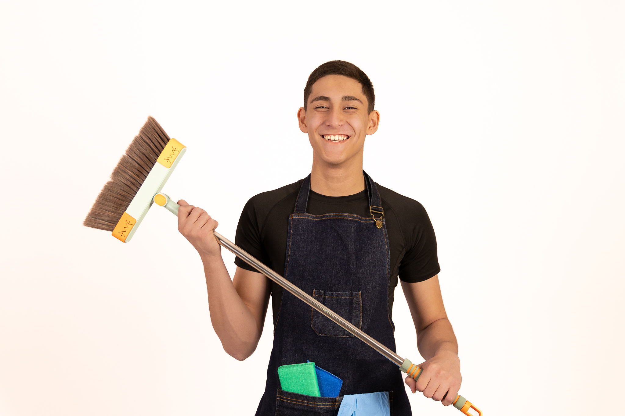 Young man holding a broom and smiling Young man holding a broom and smiling