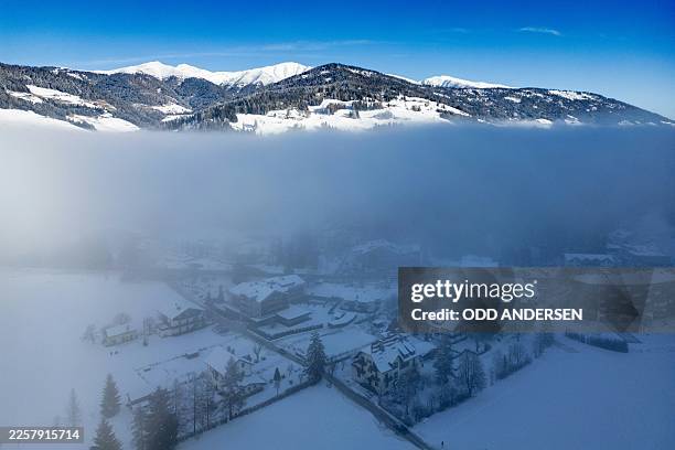 Mountain peaks are seen above the fog that clouds the village of Toblach, between the Olympic venues in Cortina and Antholz, northern Italy prior to...