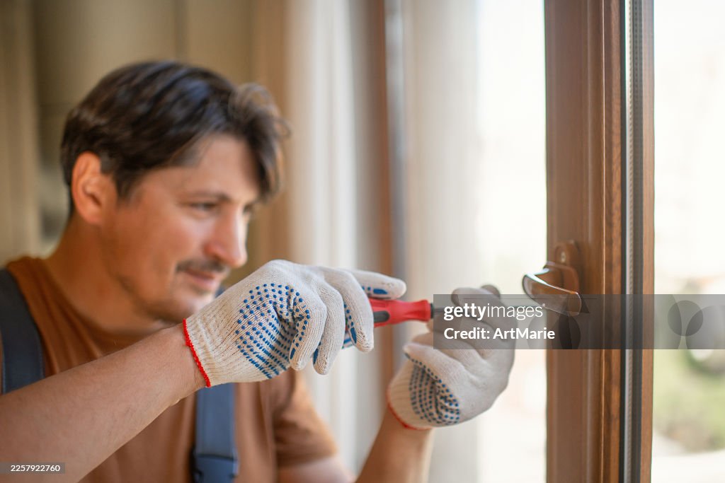Man with screwdriver repairing window