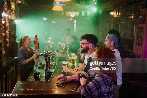 friends enjoying beers at irish pub social gathering - irish culture stock pictures, royalty-free photos & images