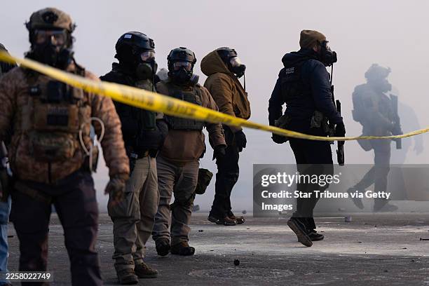 Federal agents stand in tear gas and face protesters on Nicollet Avenue near West 26th St. In south Minneapolis after Alex Pretti was fatally shot by...