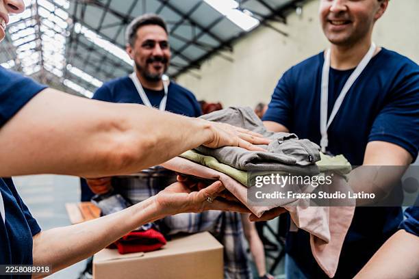 close-up of volunteers passing around clothes to donation - schenking stockfoto's en -beelden