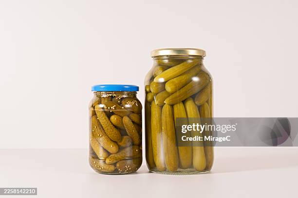 a group of pickles preserved in glass jars on beige background - cetriolino foto e immagini stock