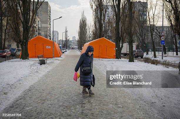 Woman walks by emergency heating points set up in a neighborhood where many buildings have been without heating and very little electricity for weeks...