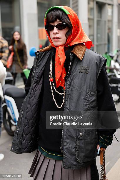 Guest wears black jumper, black Miu Miu vest jacket, grey pleated mini skirt, red hair scarf, white pearl necklace, outside Doublet, during the...