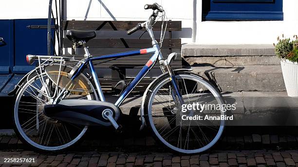 Vintage city bicycle parked near white house facade with bench, urban lifestyle and sustainable transport concept