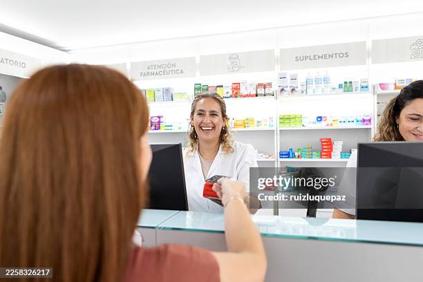 female pharmacist serving female customer at the pharmacy counter - woman at pharmacy stock pictures, royalty-free photos & images