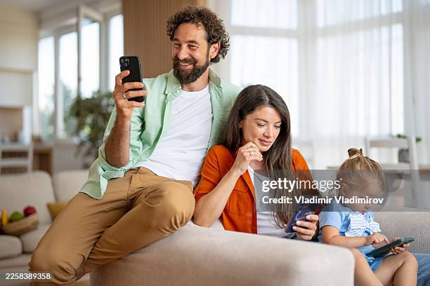 family using smartphones on couch, prioritizing screen time - phone screen time stock pictures, royalty-free photos & images