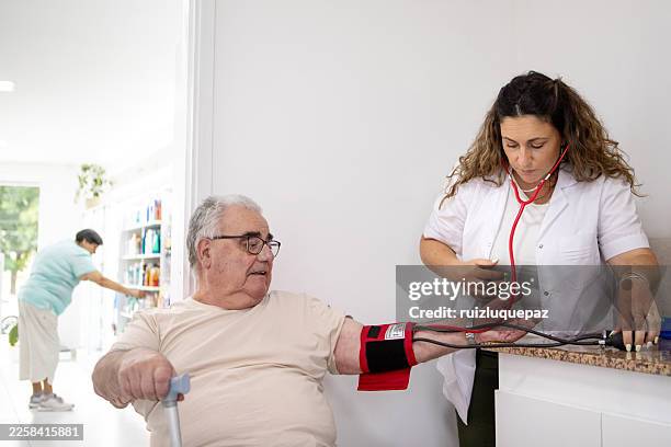 pharmacist takes the blood pressure of an elderly man - woman at pharmacy stock pictures, royalty-free photos & images