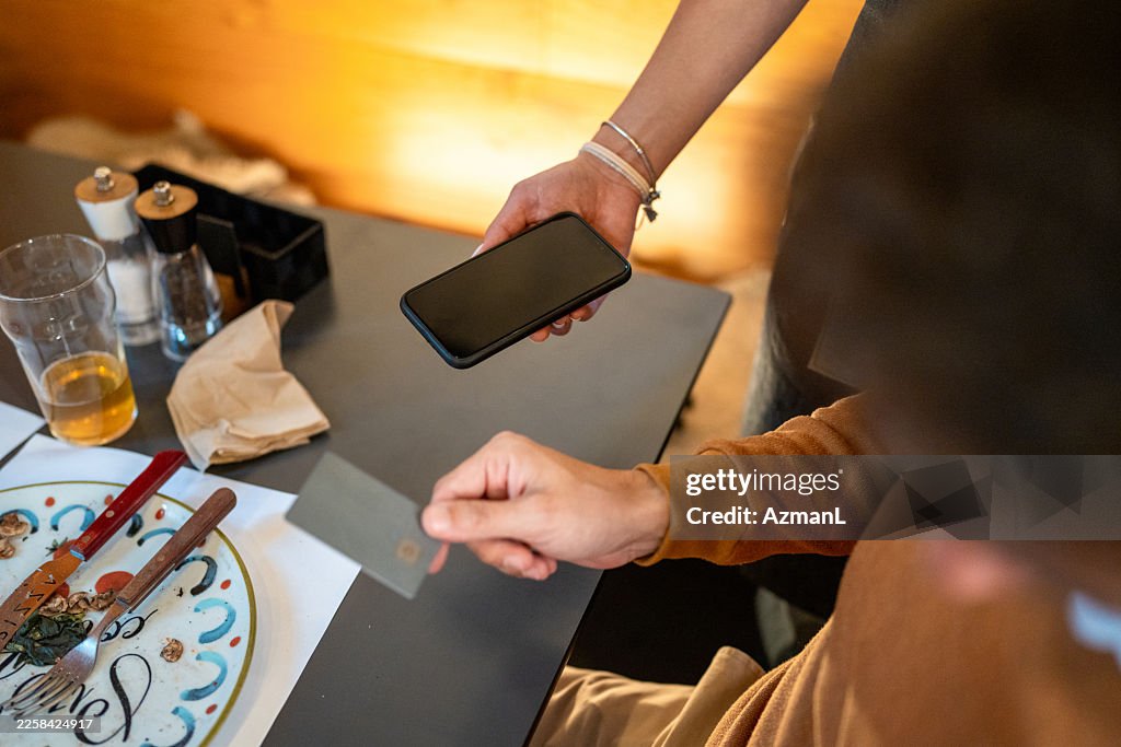 Caucasian Man Paying Restaurant Bill with Credit Card Using Smartphone Terminal