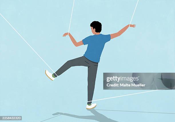 young man restrained by strings tied to wrists and ankles trying to walk - puppet stock illustrations
