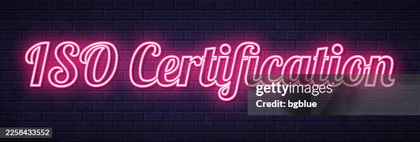 iso certification - glowing neon text on brick wall background - certificate iso stock illustrations