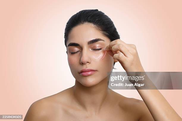 woman removing eye makeup with patch for beauty routine - faltenreduktion stock-fotos und bilder